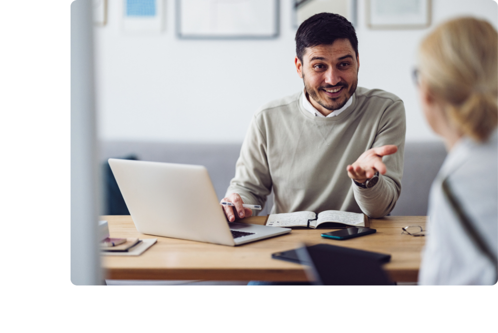 Homme souriant en rendez-vous avec une patiente et utilisant son ordinateur