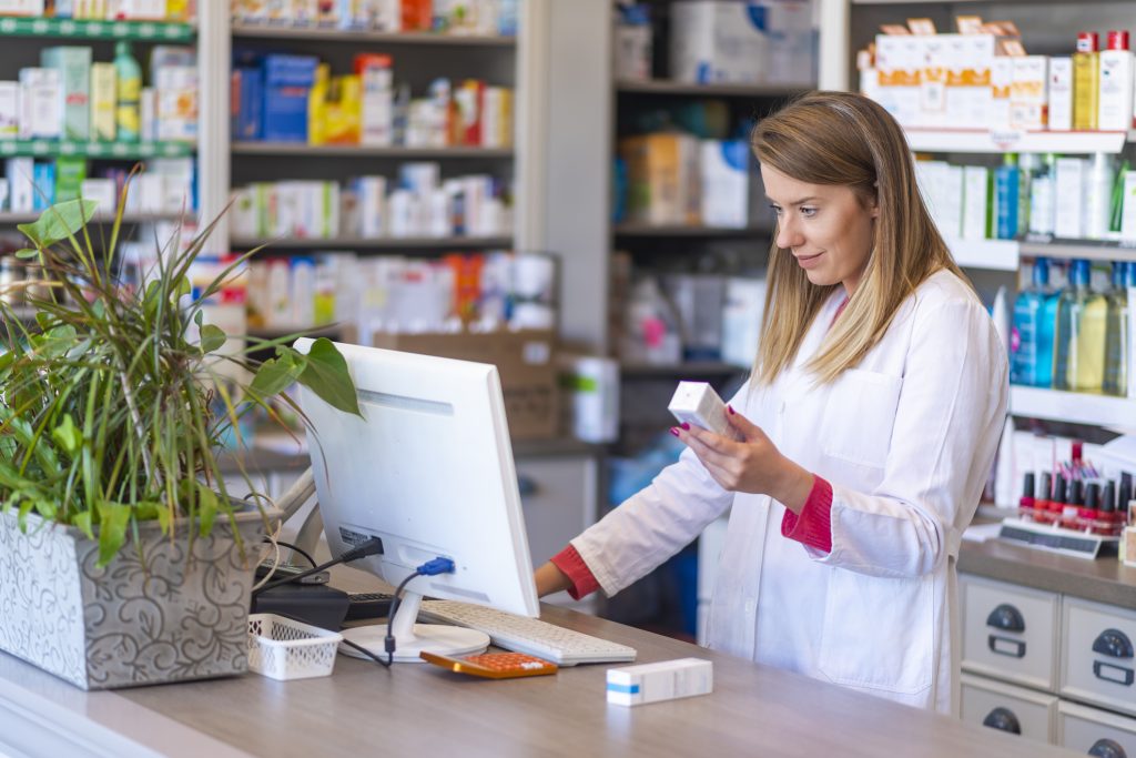 Pharmacienne tenant un produit et cherchant des informations sur un ordinateur