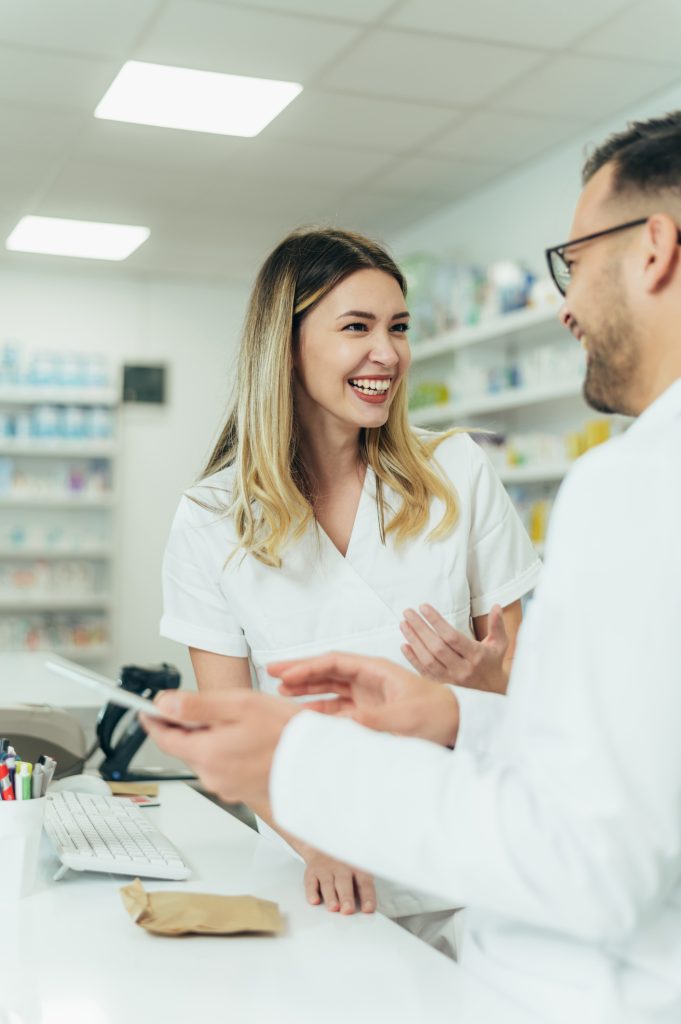pharmacienne blonde souriante à un collègue au comptoir