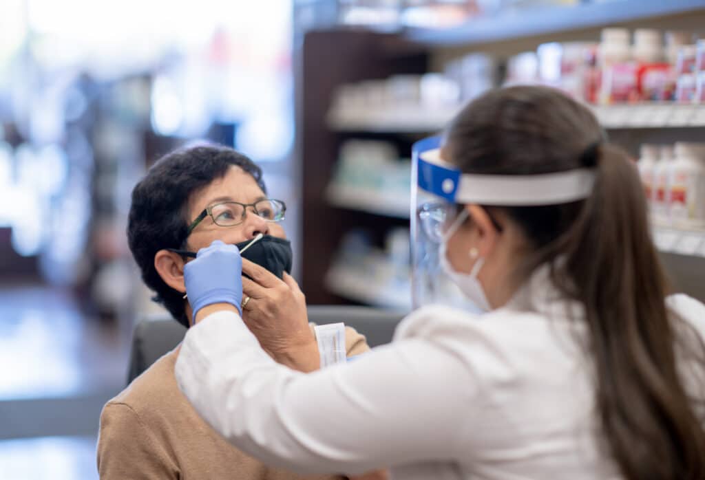 Pharmacienne insérant un test antigénique dans le nez de sa patiente