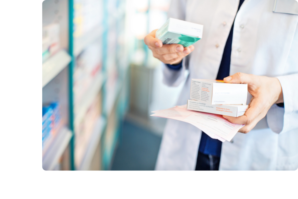 Mains d'une pharmacienne qui porte 3 boîtes de produits