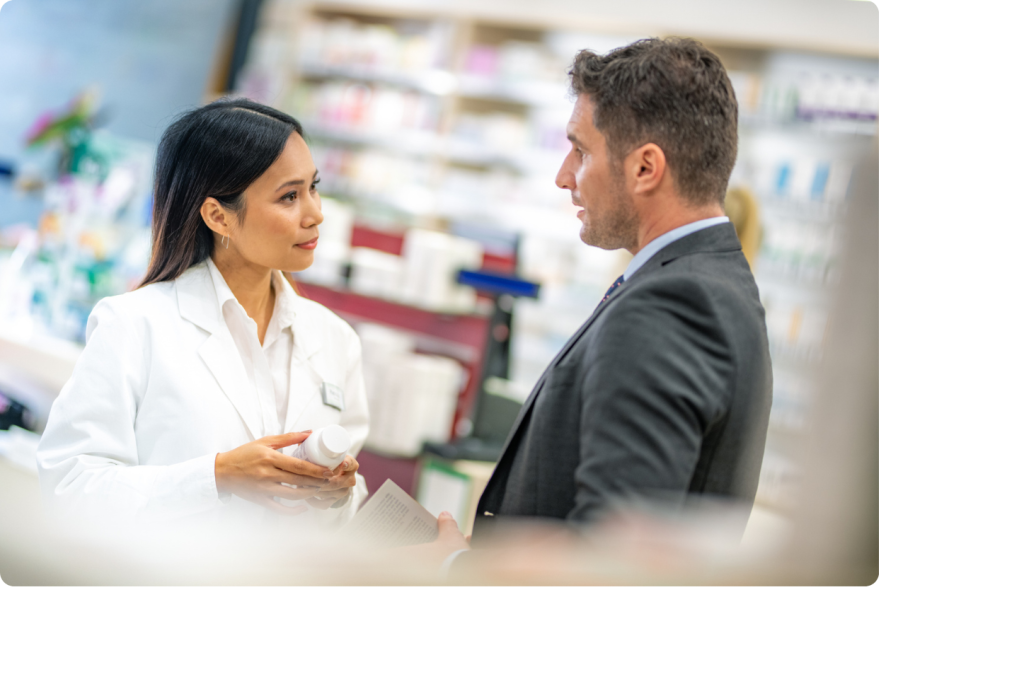Pharmacienne en blouse blanche qui discute avec un homme en veste grise