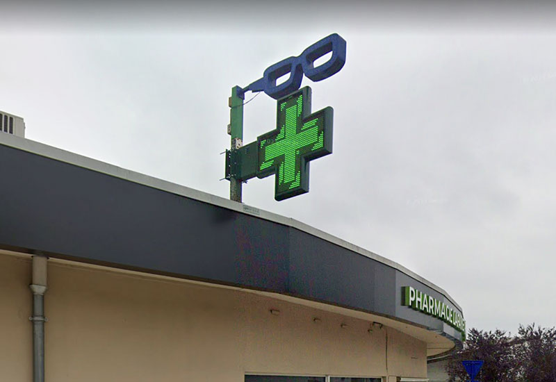 Croix de pharmacie préprogrammée sur devanture avec ciel gris