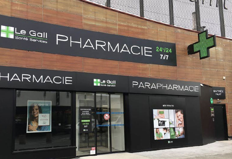 Croix de pharmacie programmable sur une devanture marron de pharmacie