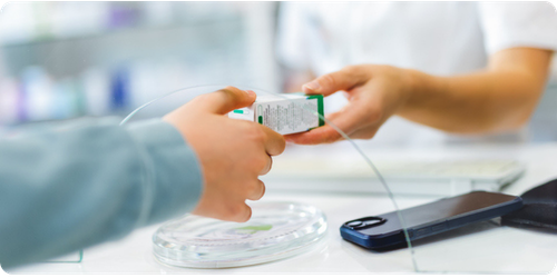 Produit pharmaceutique remis d'une main d'un pharmacien dans la main d'une patiente