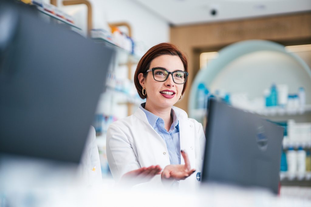 Pharmacienne en blouse blanche souriante au comptoir